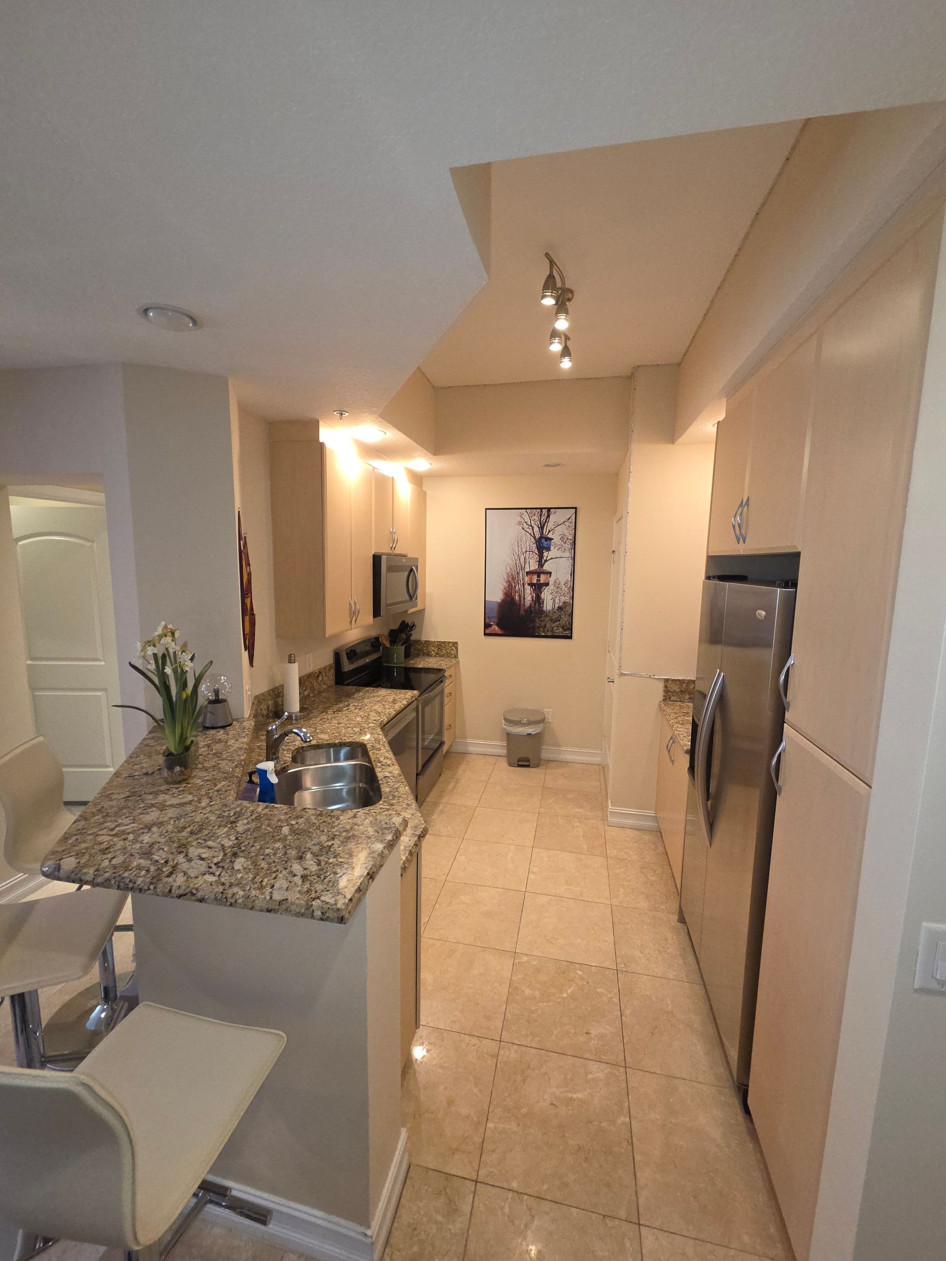 Kitchen with granite countertop, stainless steel appliances, and beige tile floor.