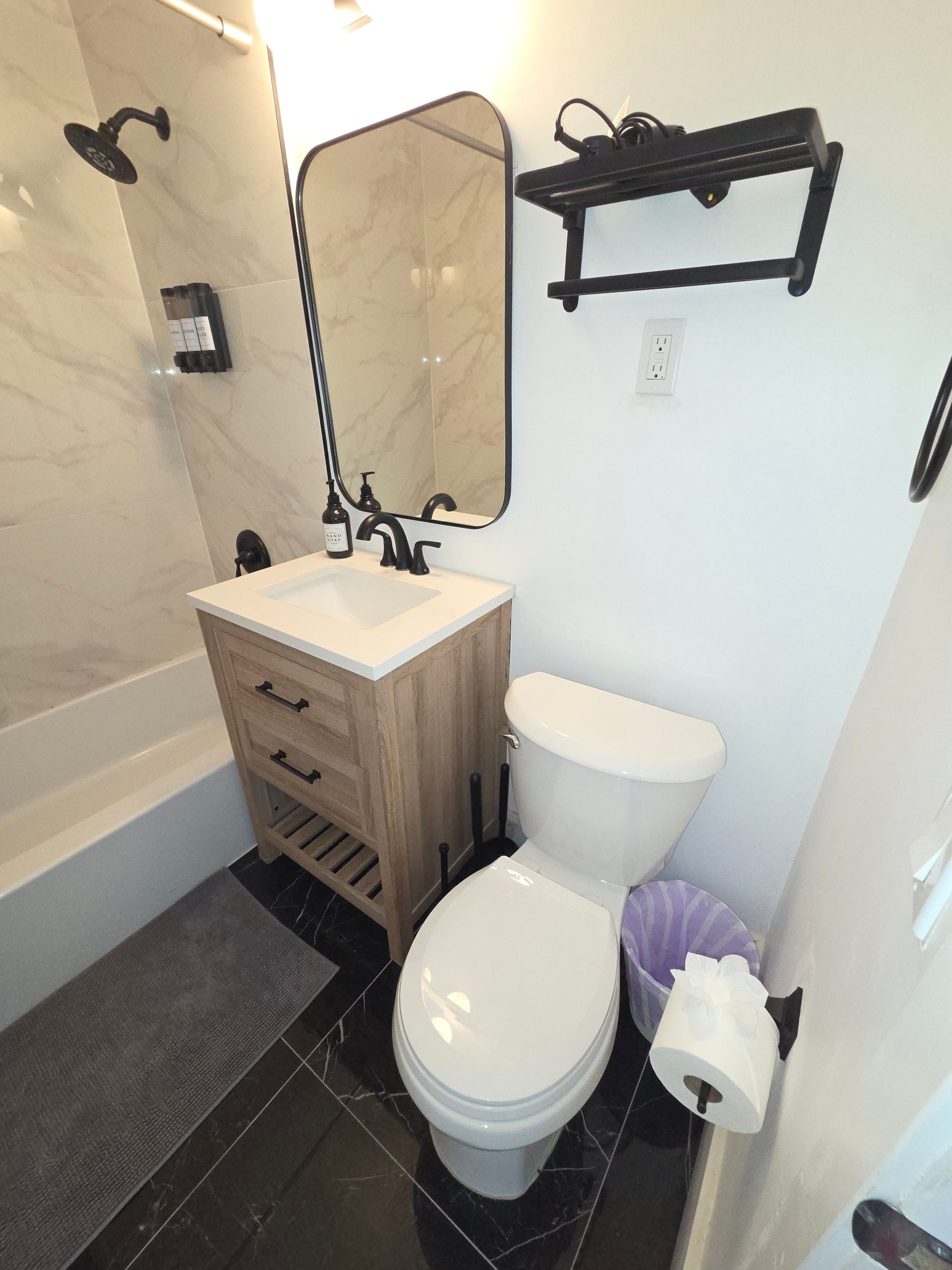 Bathroom with vanity, toilet, and shower, featuring black and white decor.