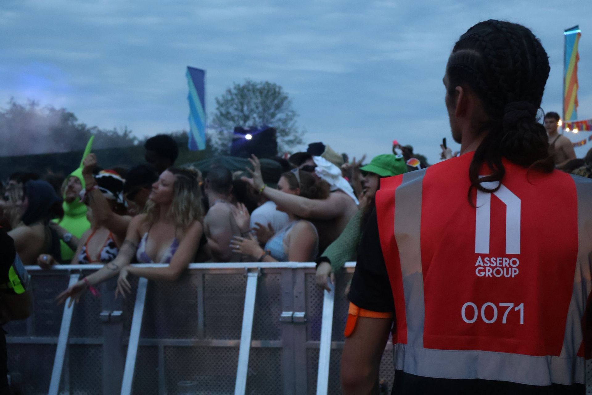 Festival crowd behind a barrier, security guard in focus.