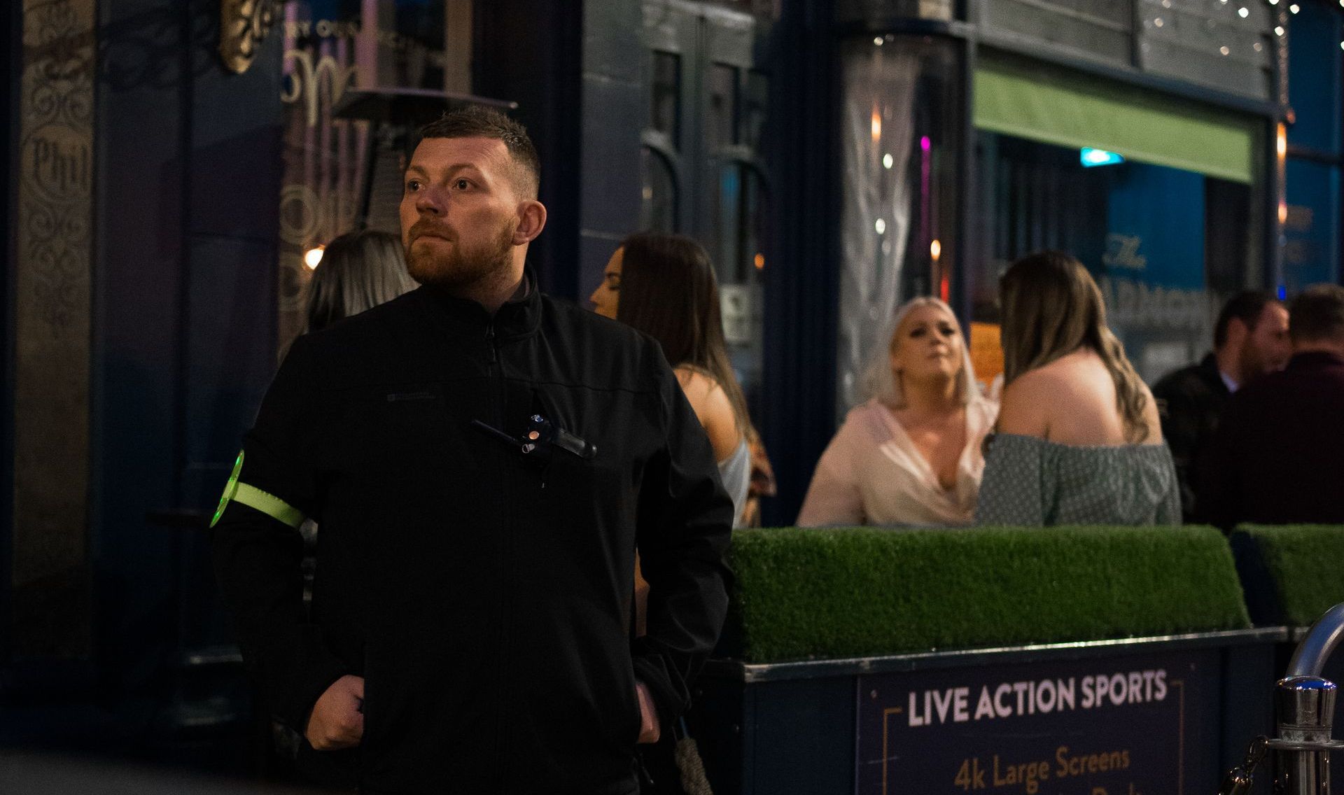A man in a black jacket is standing in front of a crowd of people.