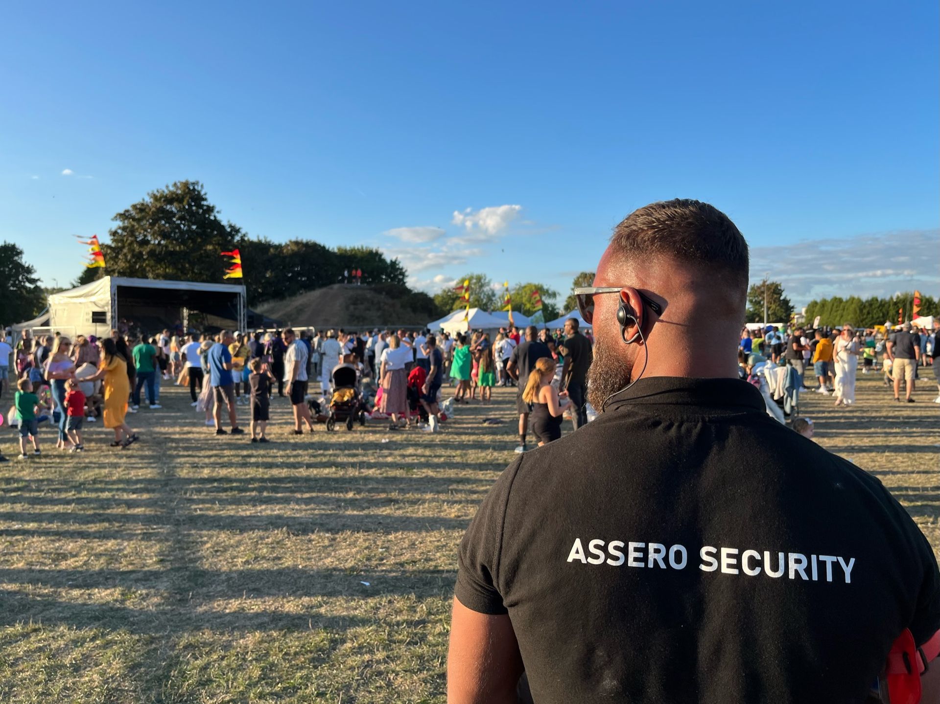 Security guard at an outdoor event, crowd in background.