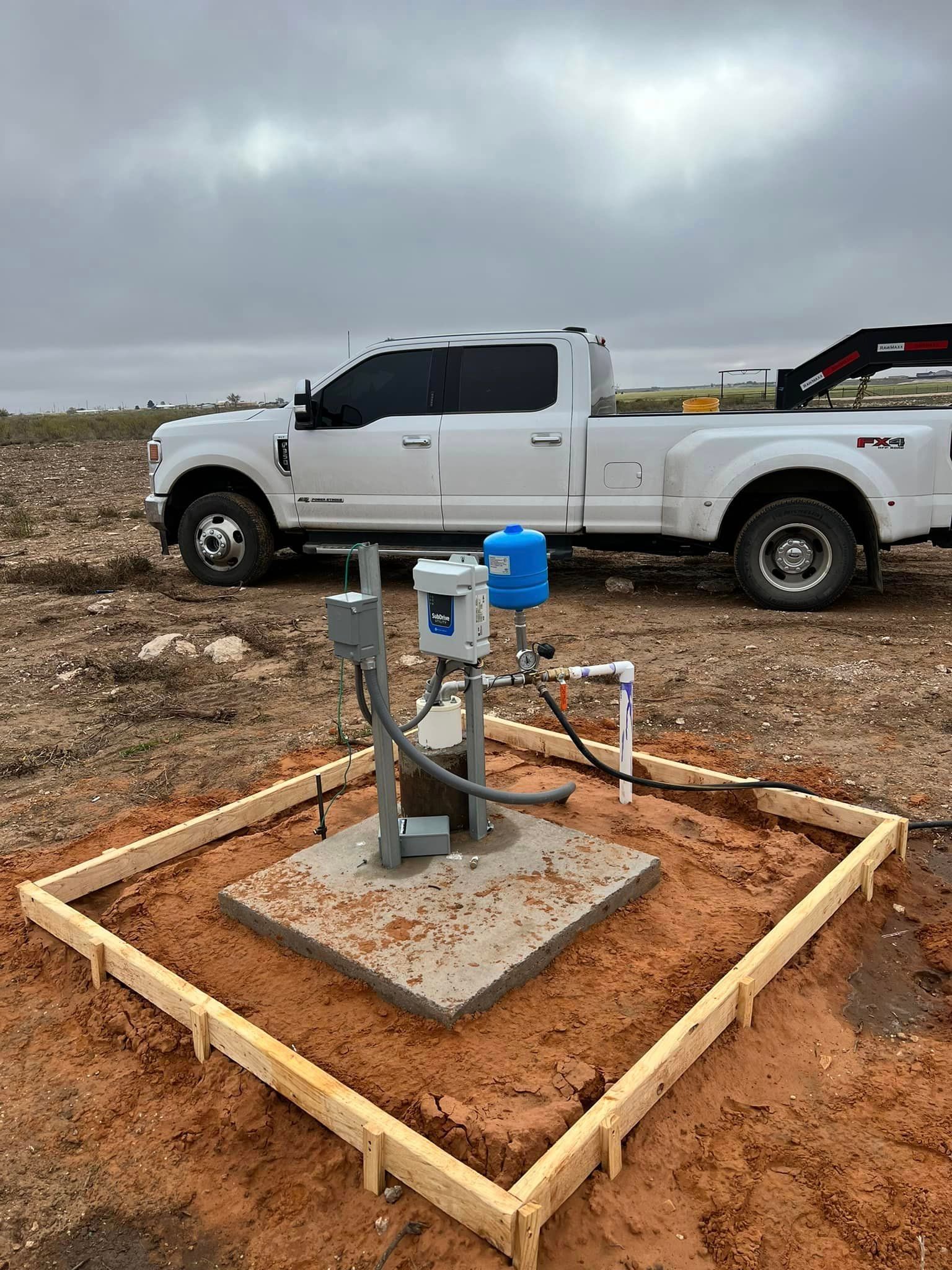 A white truck is parked in a dirt field next to a water pump — Seminole, TX — Shpuetz Drilling