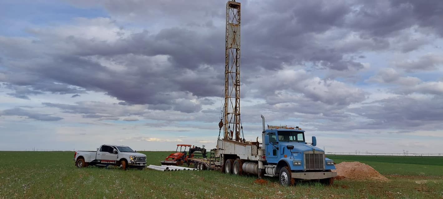 A truck is driving through a field next to a drilling rig — Seminole, TX — Shpuetz Drilling