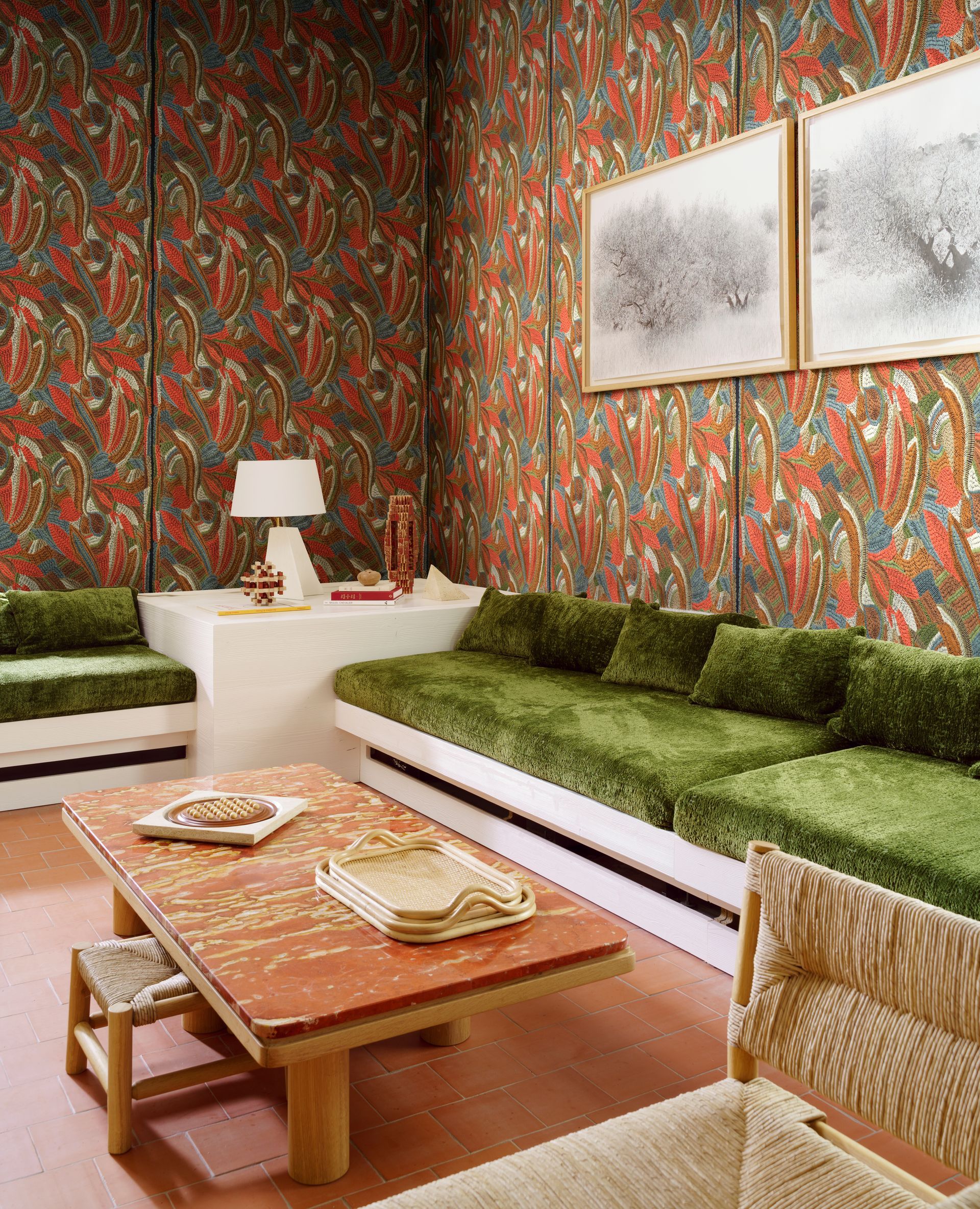 Soggiorno con carta da parati a motivi, divani verdi e un tavolino da caffè color rosso-marrone.