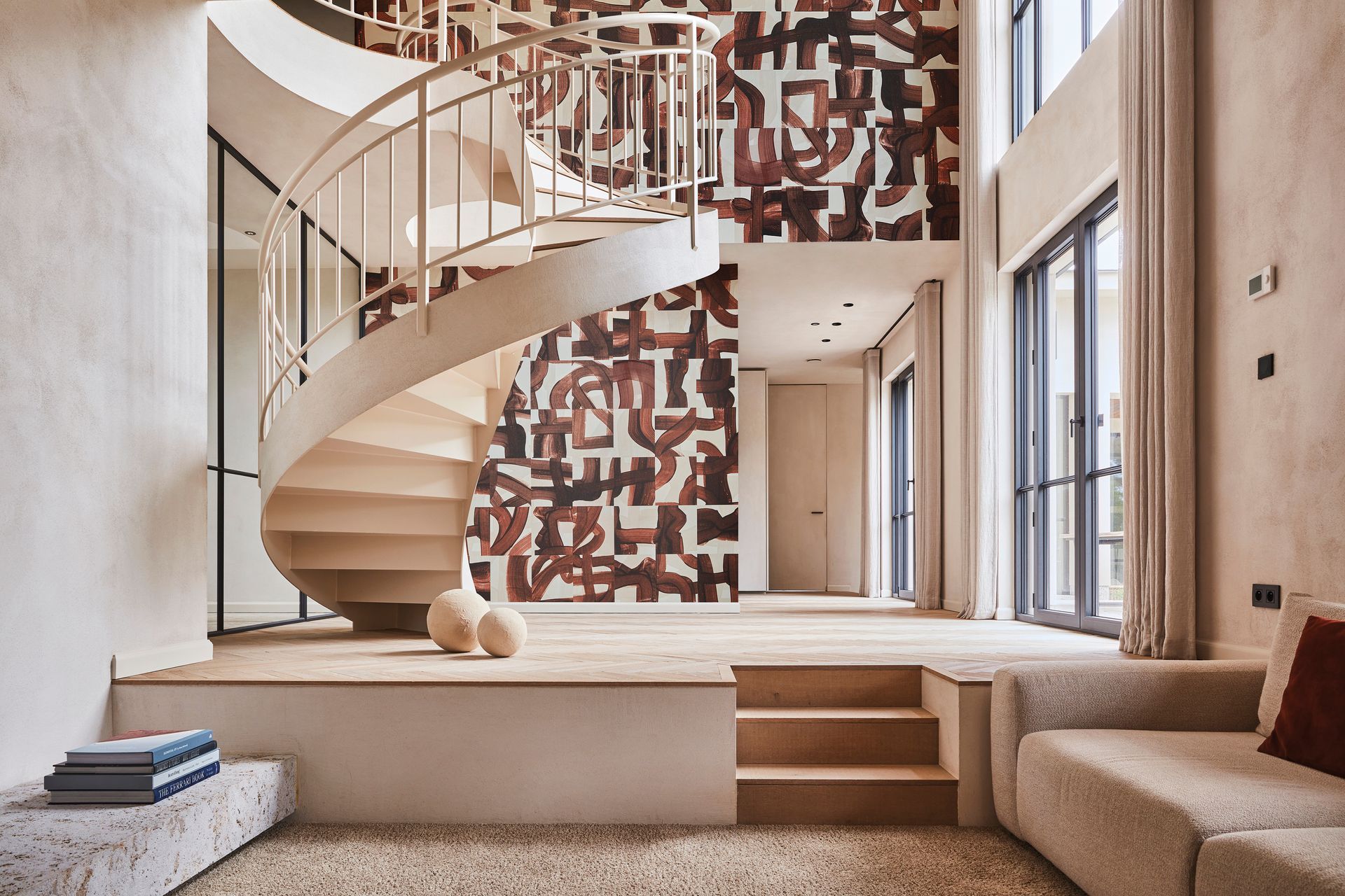 Scala a chiocciola in una casa moderna con opere d'arte astratte alle pareti e pavimento rialzato.