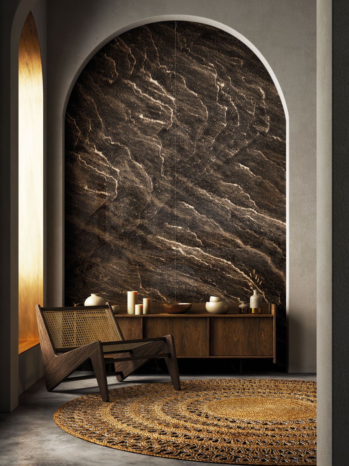 Interno con parete ad arco, marmo scuro, mobile in legno, sedia intrecciata e tappeto rotondo.