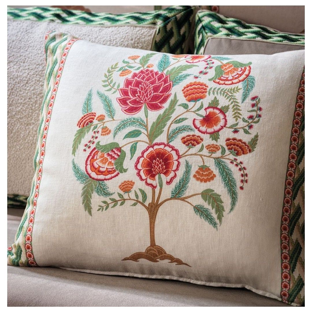 Cuscino ricamato con motivo floreale ad albero nei colori rosso, arancione, verde e marrone su sfondo crema.