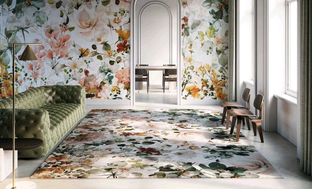 Soggiorno con carta da parati floreale, tappeto, divano verde, sedie in legno e un arco.