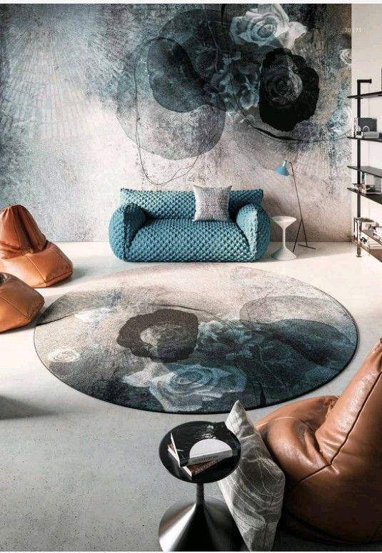 Soggiorno con divano blu, poltrone a sacco in pelle e tappeto circolare a fiori. Combinazione di colori grigio e blu.