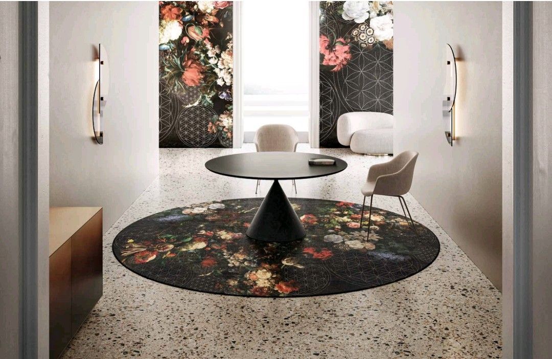 Una moderna sala da pranzo con un tavolo rotondo nero, un tappeto floreale e due pannelli floreali alla parete.