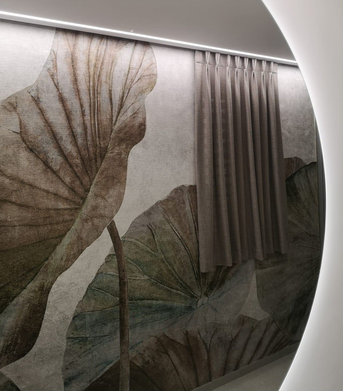 Una tenda beige è appesa davanti a un murale botanico con grandi foglie, illuminato dall'alto.