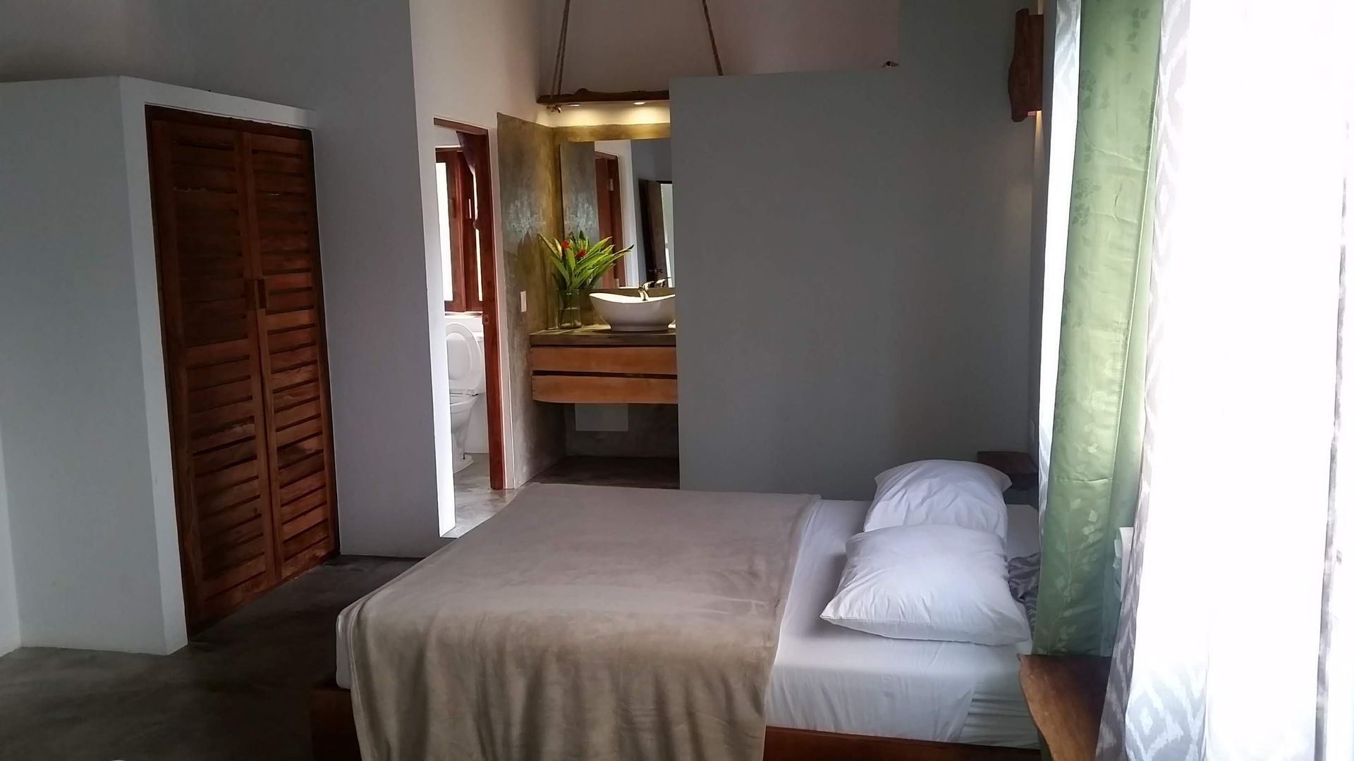 Bedroom with a bed, wooden closet, and a partially visible bathroom.