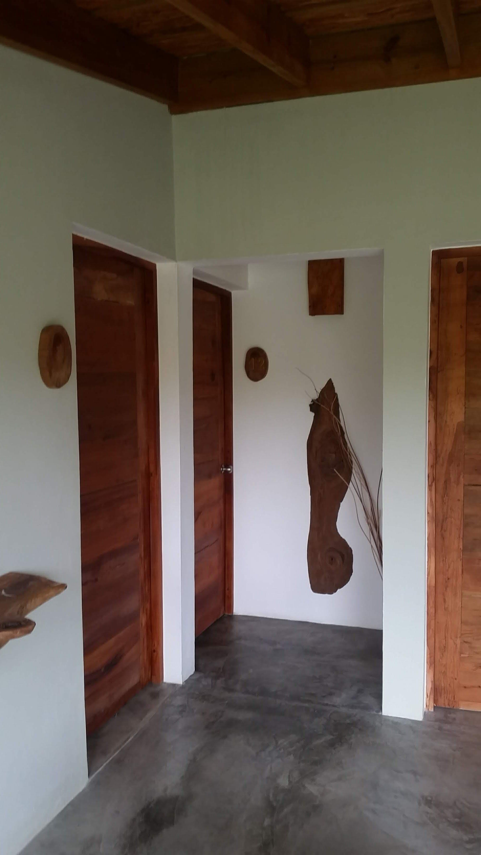 Interior hallway with three wooden doors, white walls, and a dark floor.