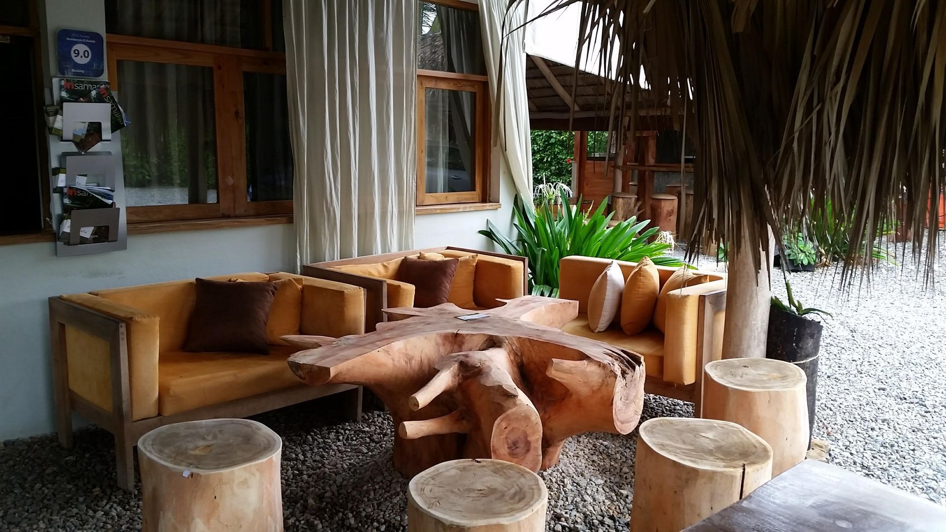 Outdoor seating area with wood furniture and a rustic tree-stump table and stools.