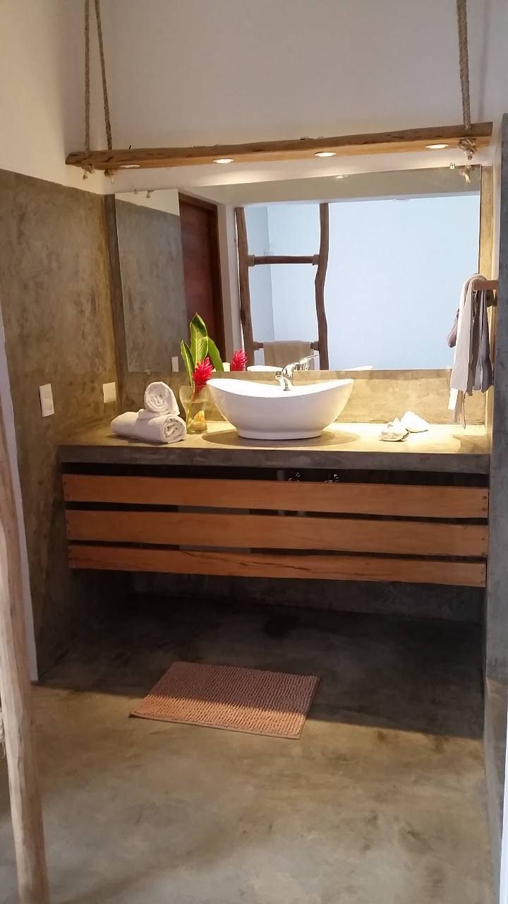 Bathroom with a wooden vanity, vessel sink, and large mirror. Neutral tones, towel rack on the right.