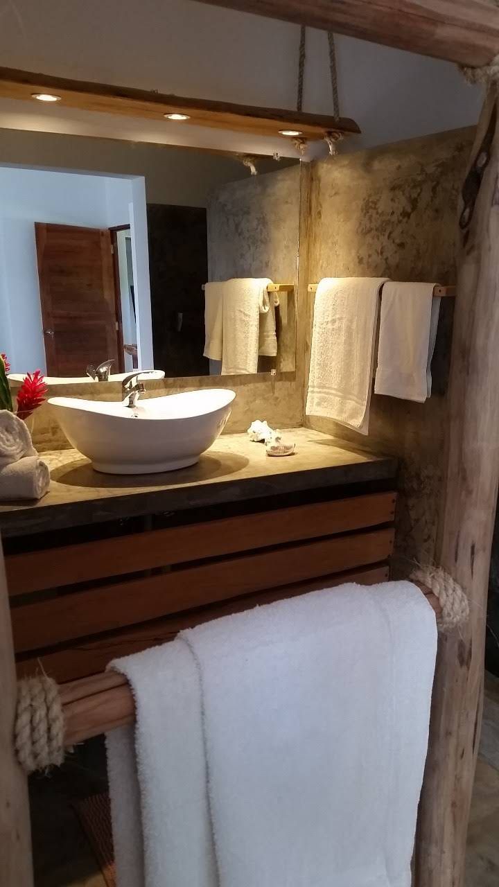 Bathroom with a vessel sink, wood vanity, and towels; natural stone wall and rustic wood accents.