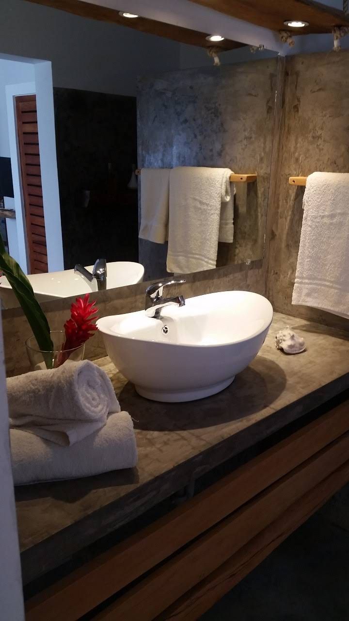 Bathroom with a white bowl sink, gray countertop, large mirror, and stacked white towels.
