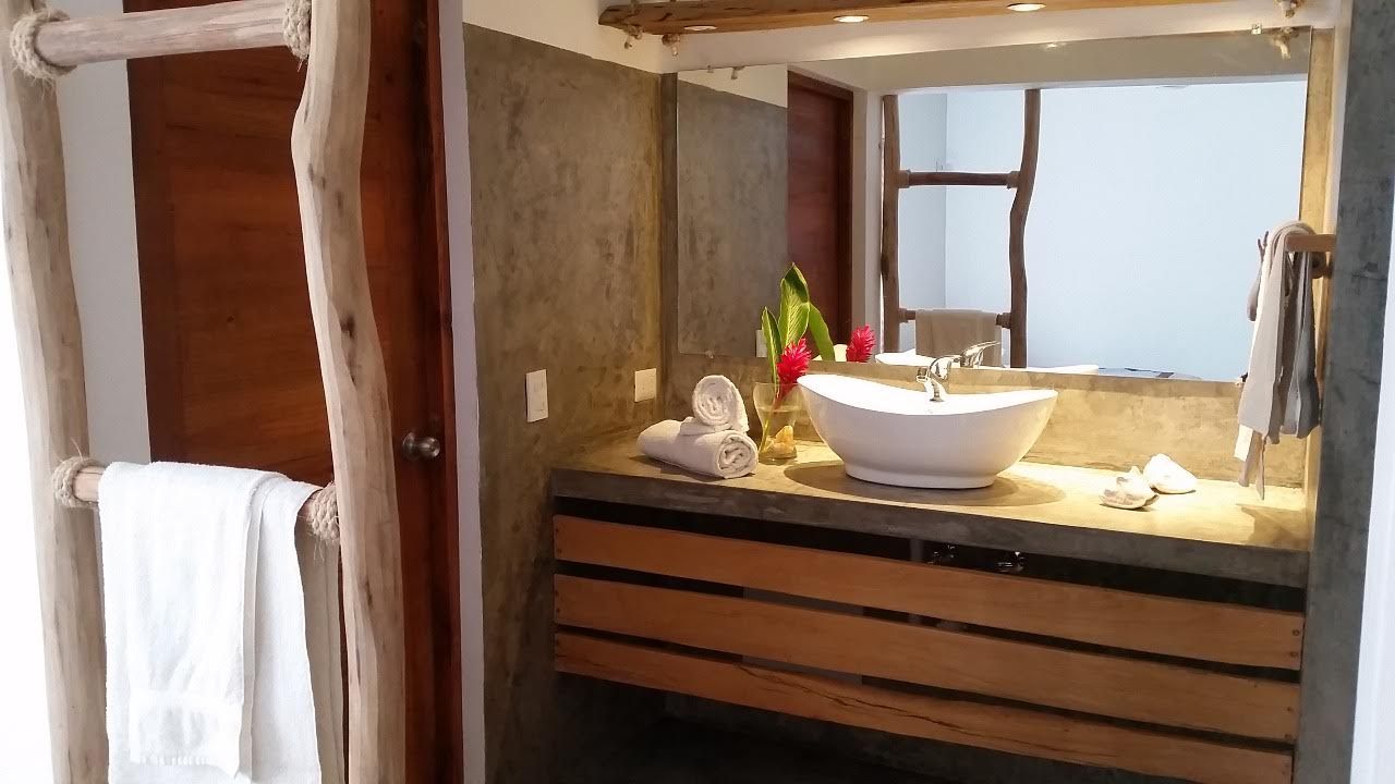Bathroom with wooden accents, white sink, towels, and a concrete countertop.