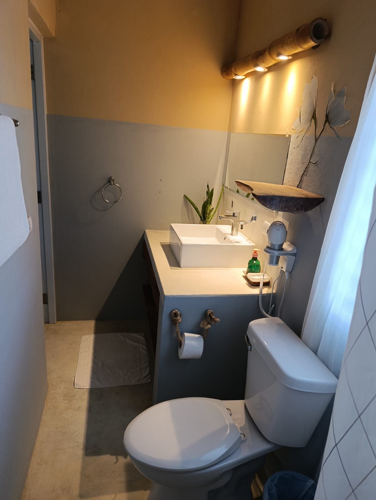 Bathroom with a white toilet, sink, and gray walls, with a bamboo light fixture above the mirror.