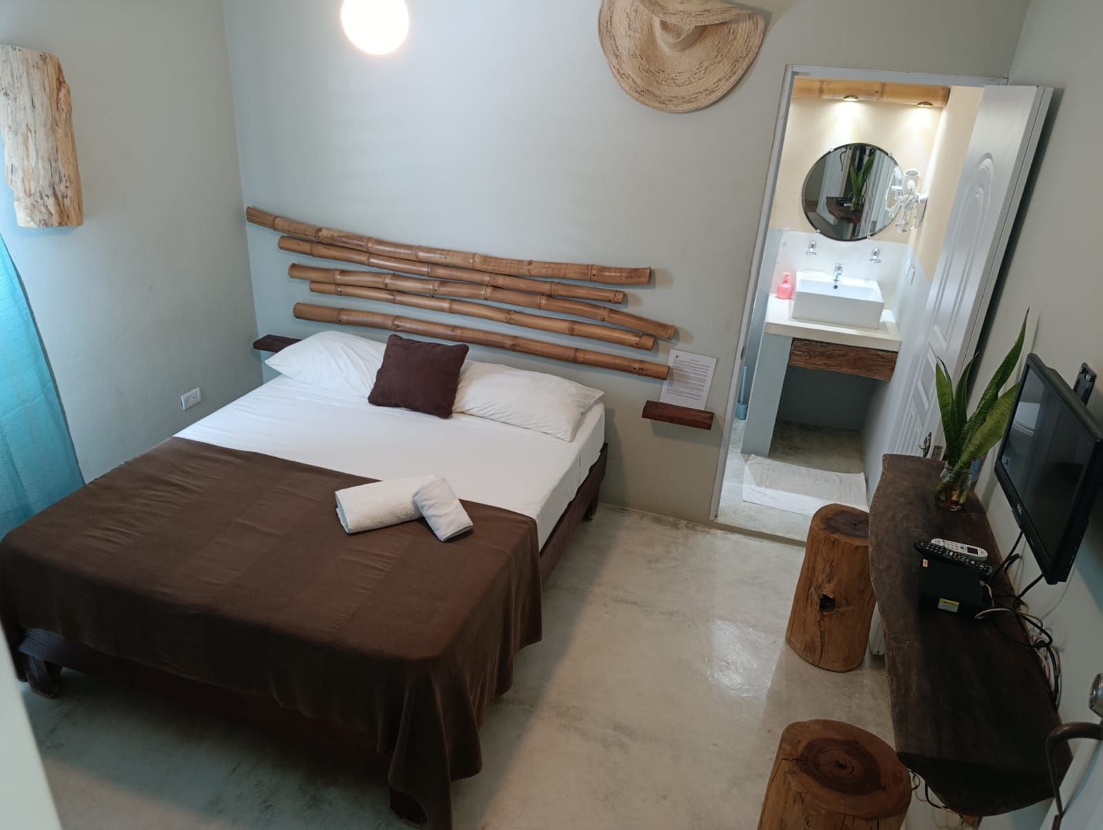 Bedroom with double bed, bamboo headboard, ensuite bathroom, and natural wood furniture.