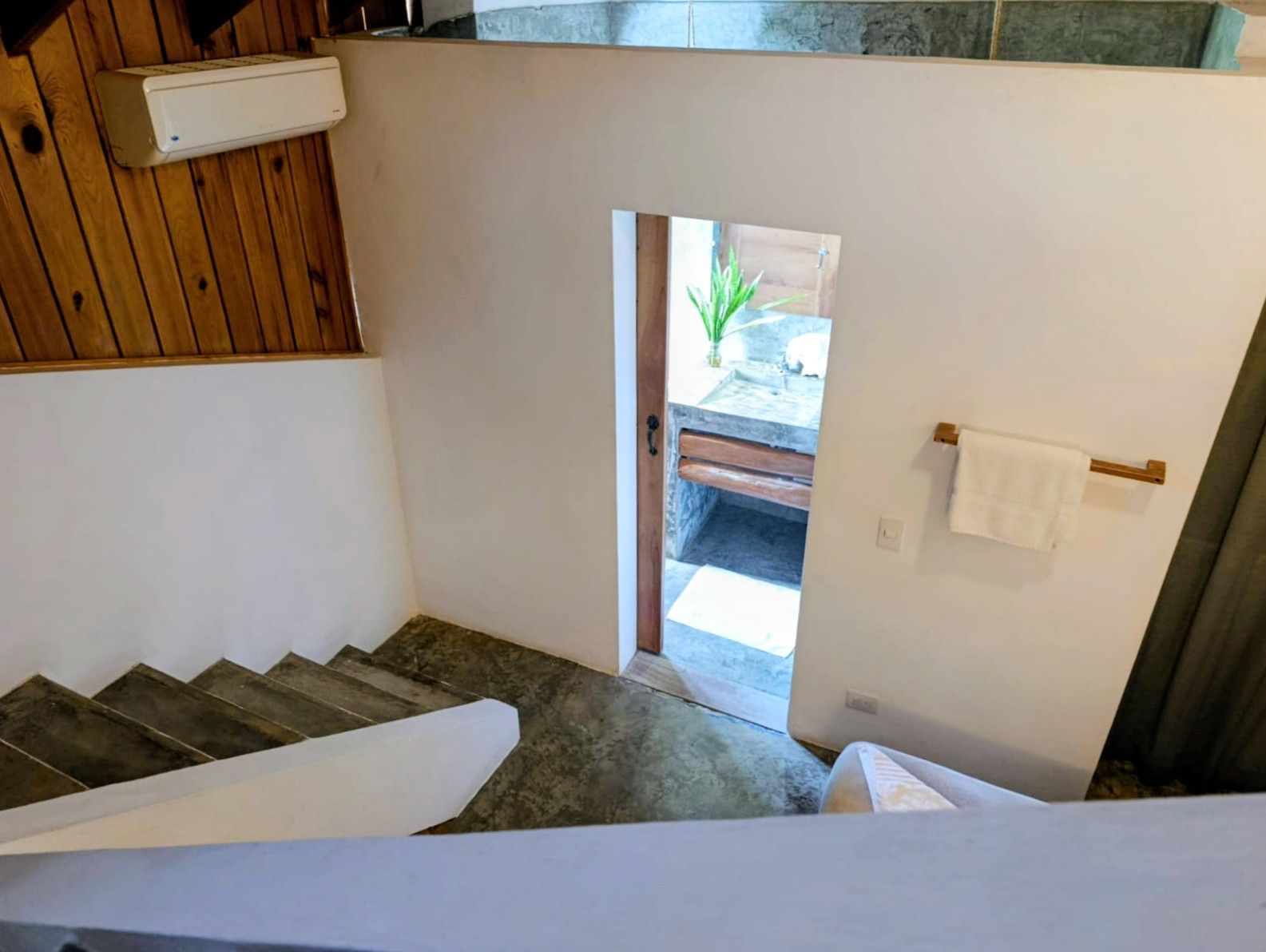 Staircase leads to a bathroom with a sink, towel rack, and wooden ceiling.