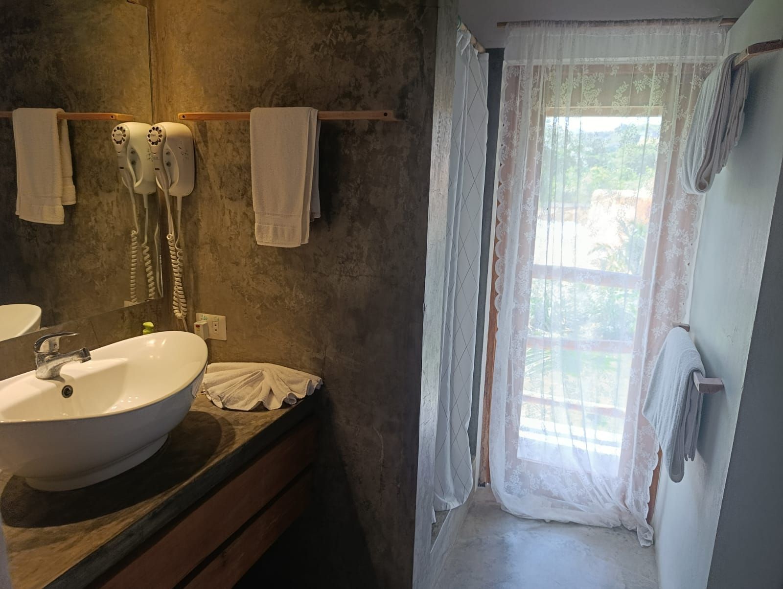 Bathroom with sink, towels, and window with sheer curtains. Gray walls.