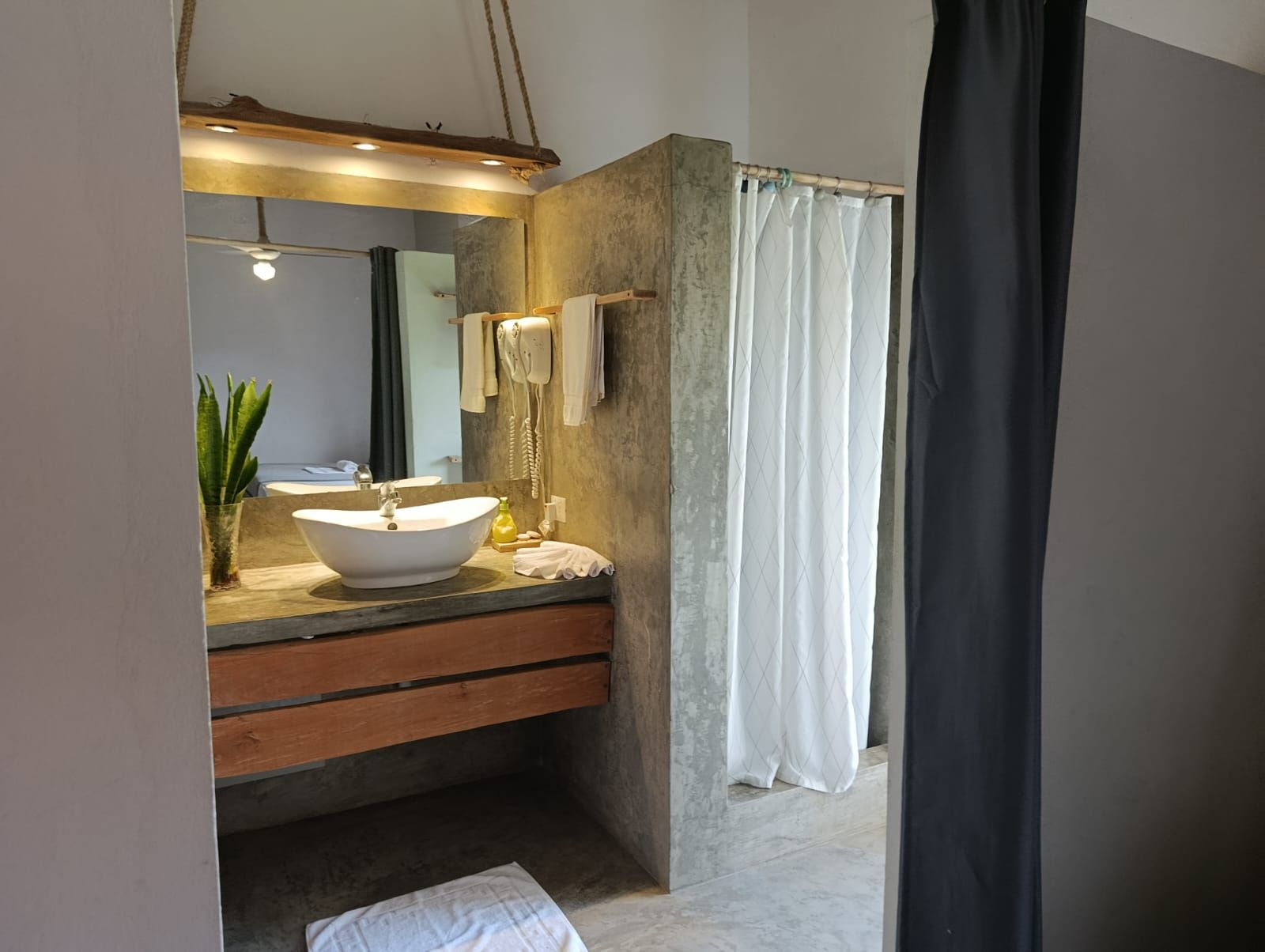 Bathroom with concrete walls, wooden vanity, and shower curtain.