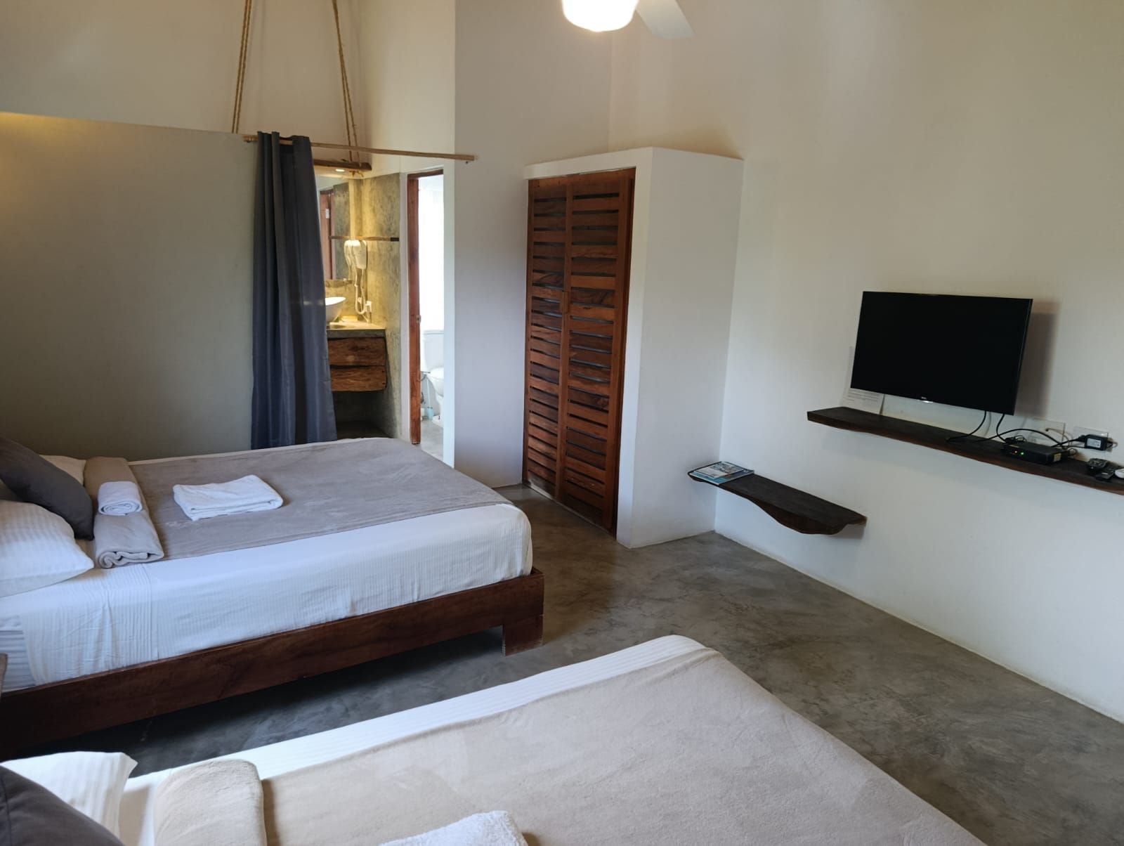 Bedroom with two beds, closet, TV, and open doorway to a bathroom.