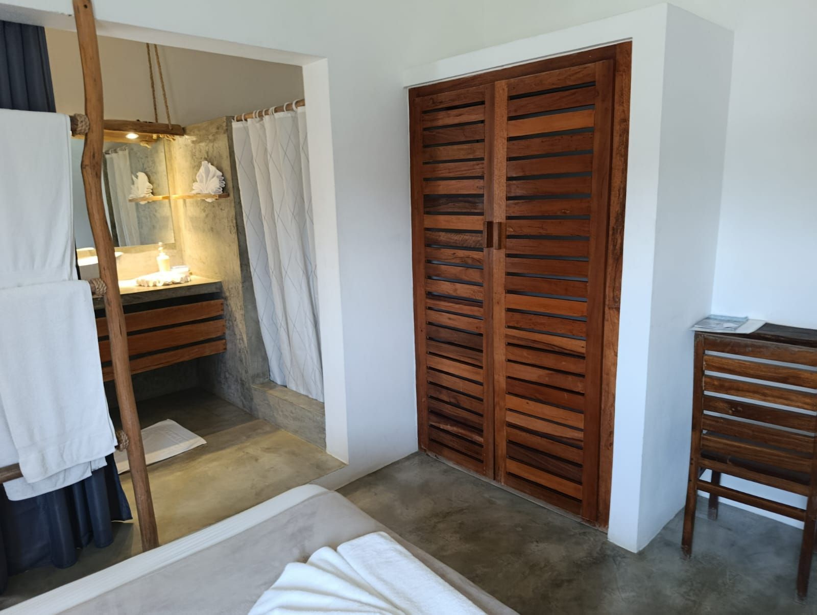 Bedroom with wooden closet and bathroom visible, featuring neutral tones and natural materials.