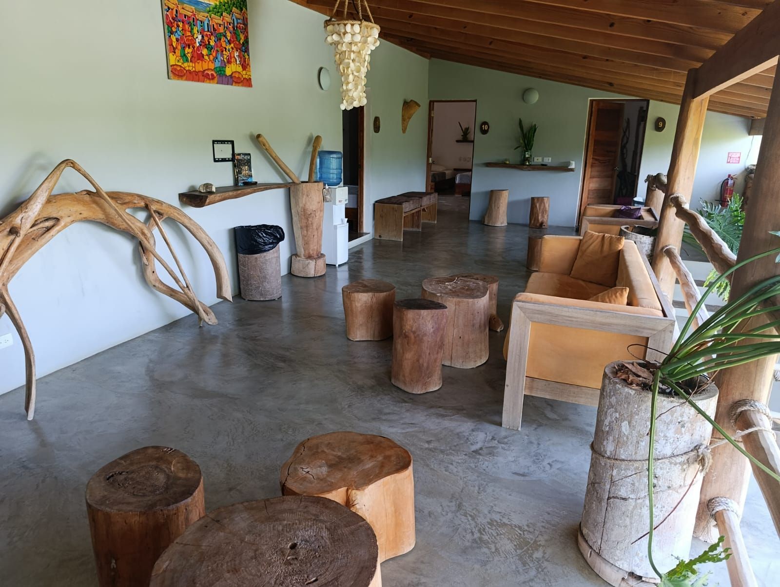 Rustic lounge area with wooden seating, natural decor, and a concrete floor.