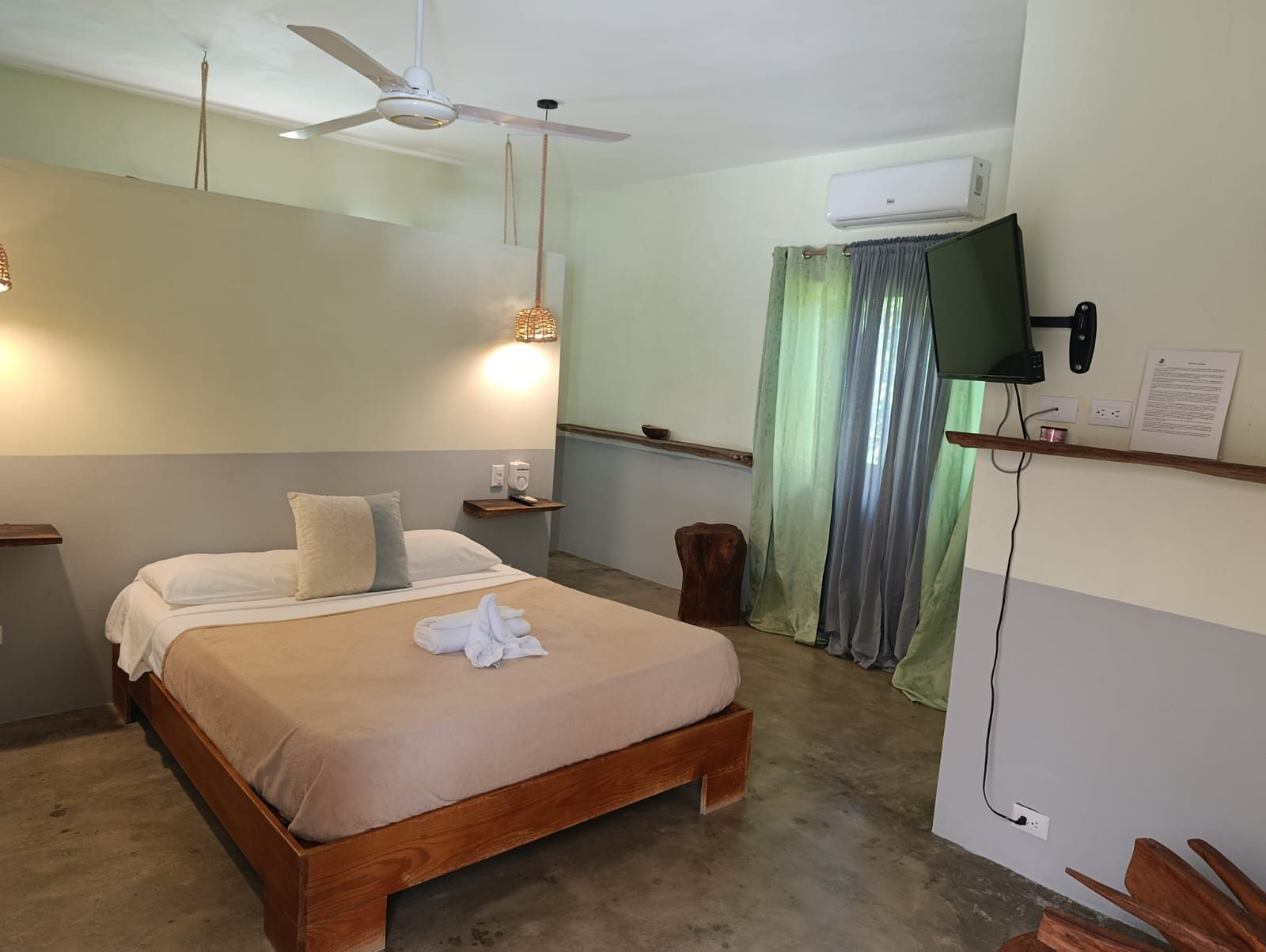 Bedroom with bed, nightstands, and TV; window with green curtains.