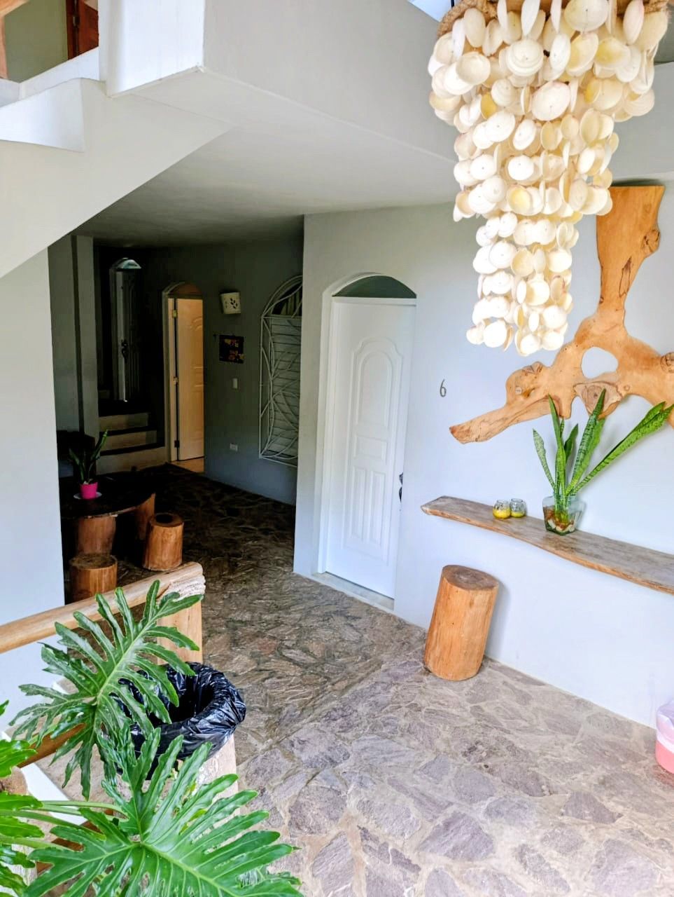 Interior hallway with stone floor, white walls, and a wood chandelier.