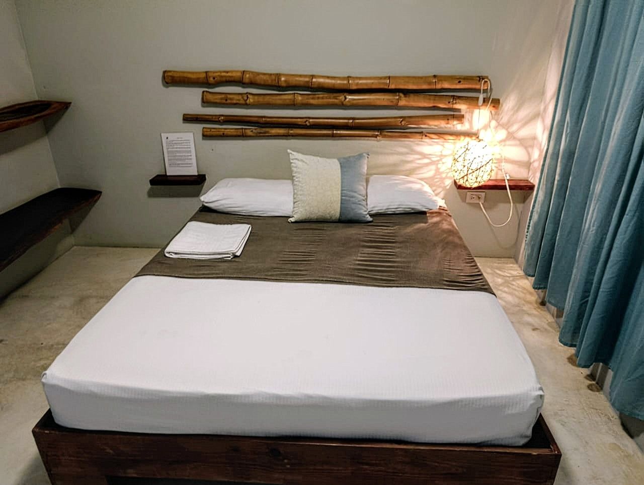 Bedroom with a wooden bed, bamboo headboard, and blue curtains.