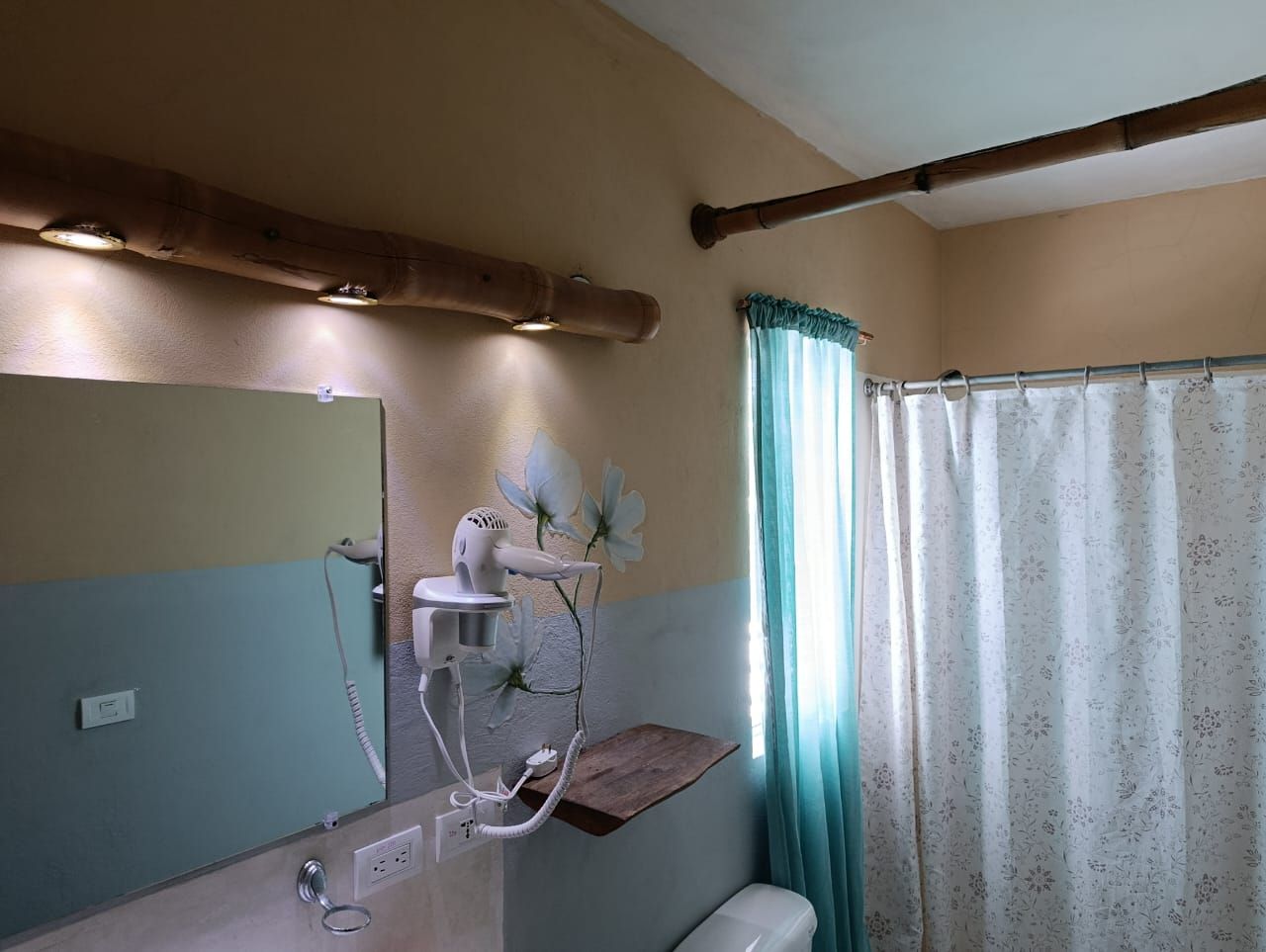 Bathroom with a mirror, hair dryer, curtain, and a bamboo rod, with a blue and beige color scheme.