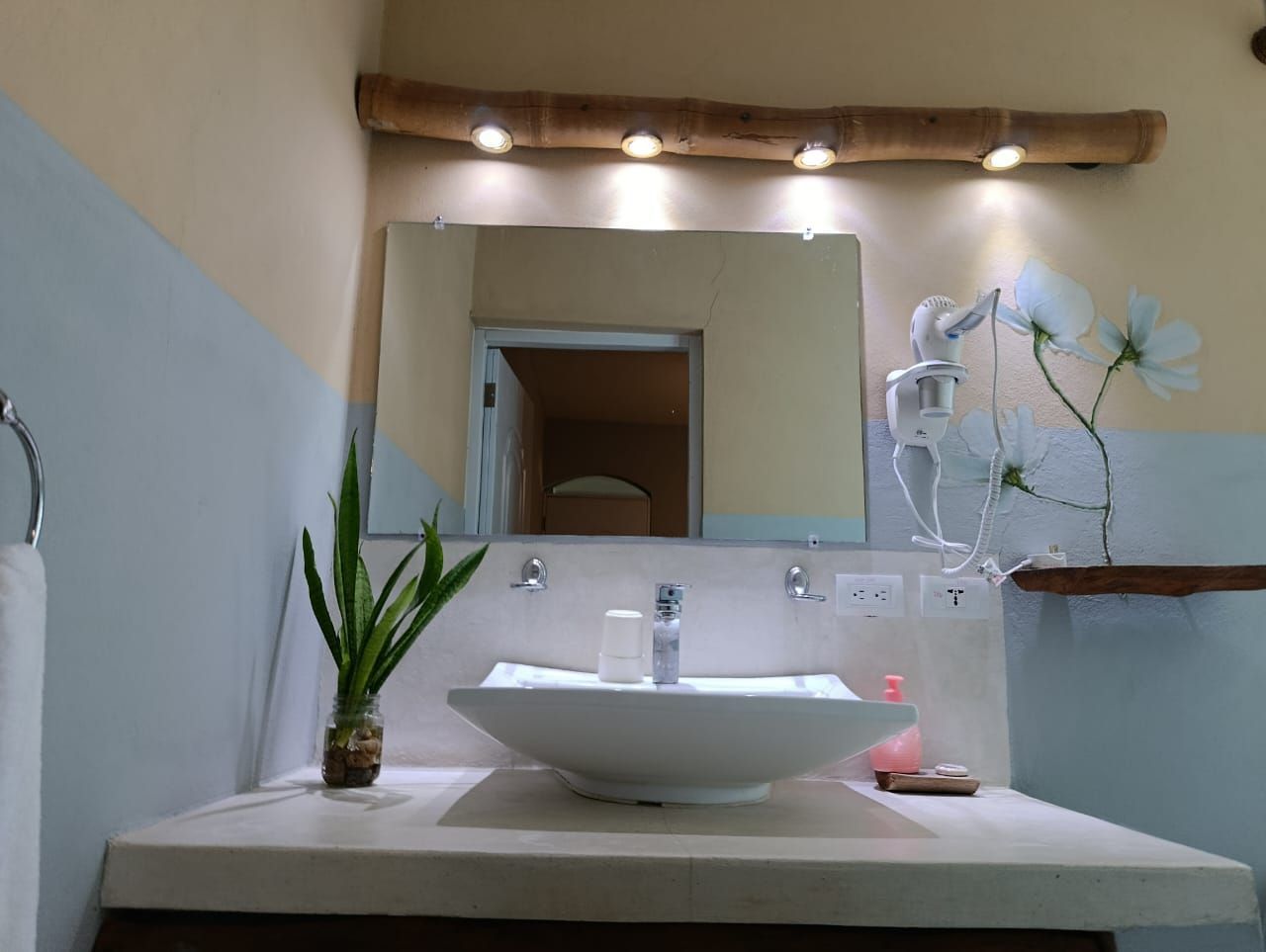 Bathroom with a vessel sink, mirror, and decorative lighting under a wooden beam.