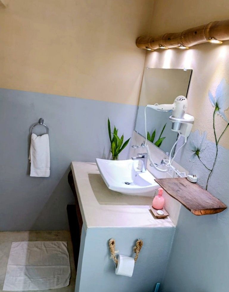 Bathroom with a white sink, mirror, towel, and toilet paper holder; blue and beige walls, wooden accents.