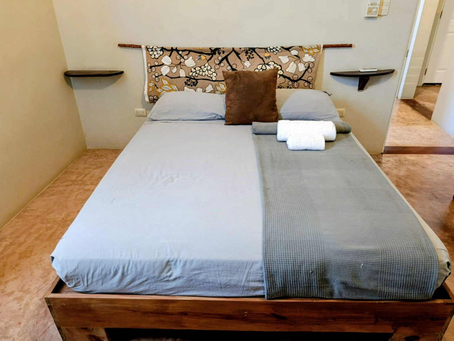 Bedroom with a wooden bed frame, gray bedding, brown pillow, and decorative headboard.