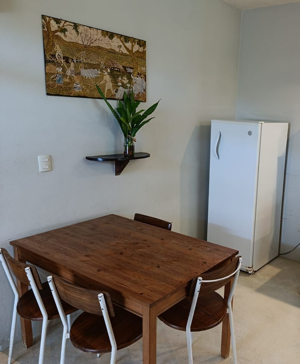 Dining area with a wooden table and chairs, a fridge, and wall art.