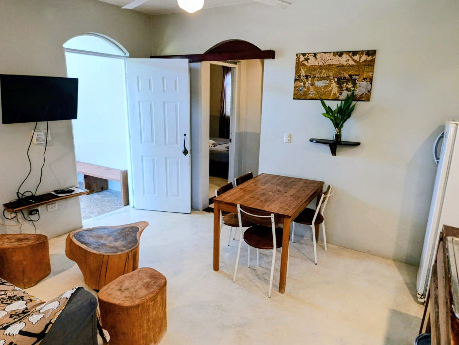 Living area with wooden furniture, open doorway to bedroom, and a small TV.