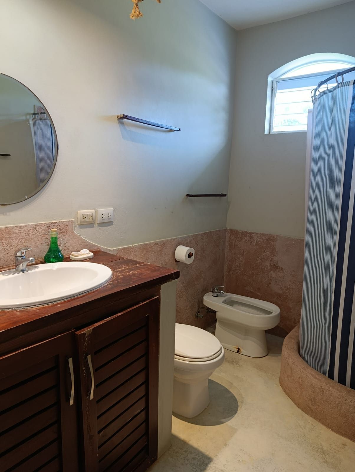 Bathroom with sink, toilet, bidet, and shower. Tan and brown hues.