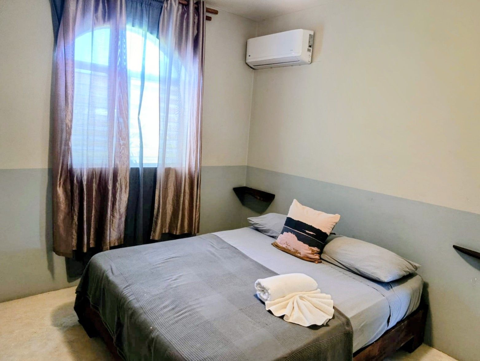 Bedroom with a bed, window with curtains, air conditioner, and two shelves.