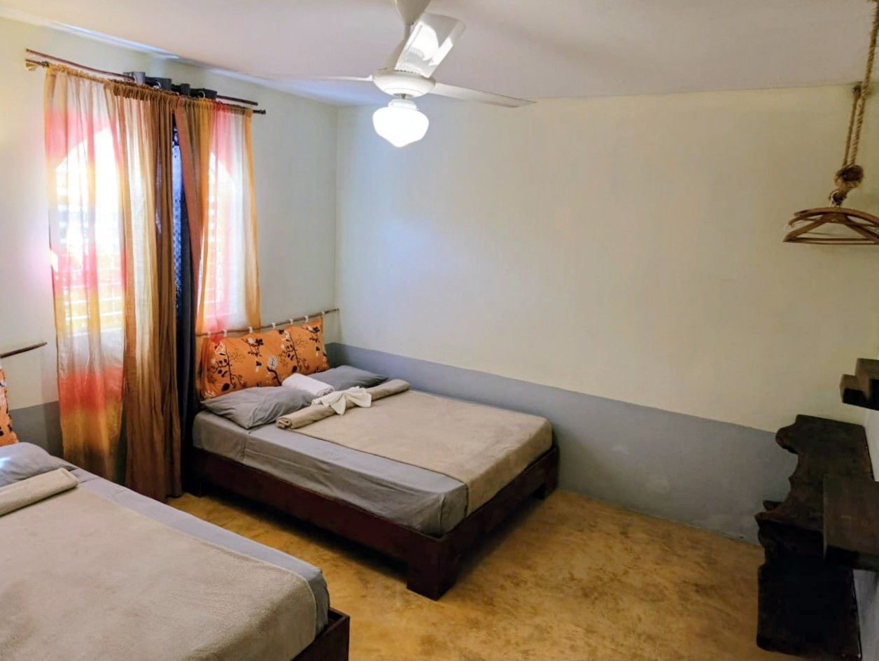 Bedroom with two beds, window with curtains, and a ceiling fan.