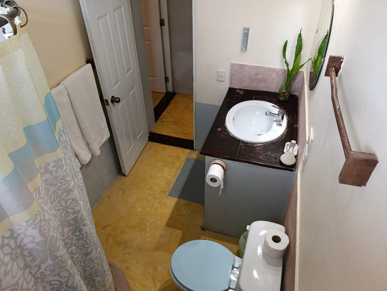 Small bathroom with toilet, sink, and shower. Yellow and gray color scheme.