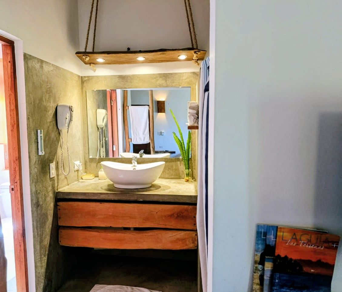 Bathroom with rustic wood vanity, vessel sink, mirror, and hanging light fixture.