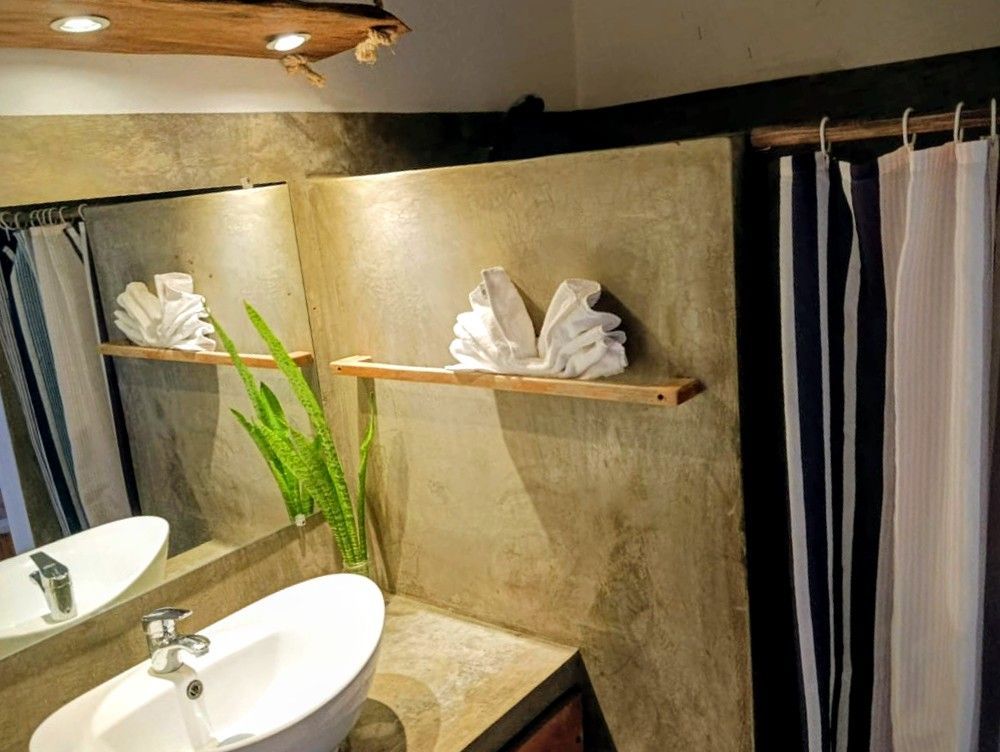 Bathroom with sink, mirror, towels folded as birds on a shelf, and shower curtain.