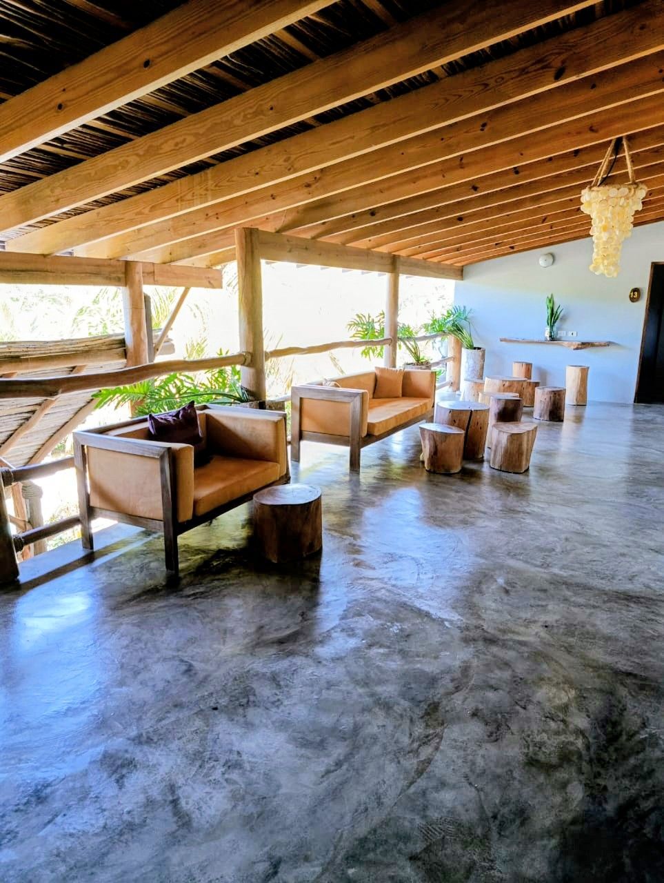 Covered patio with wooden furniture and concrete floor.