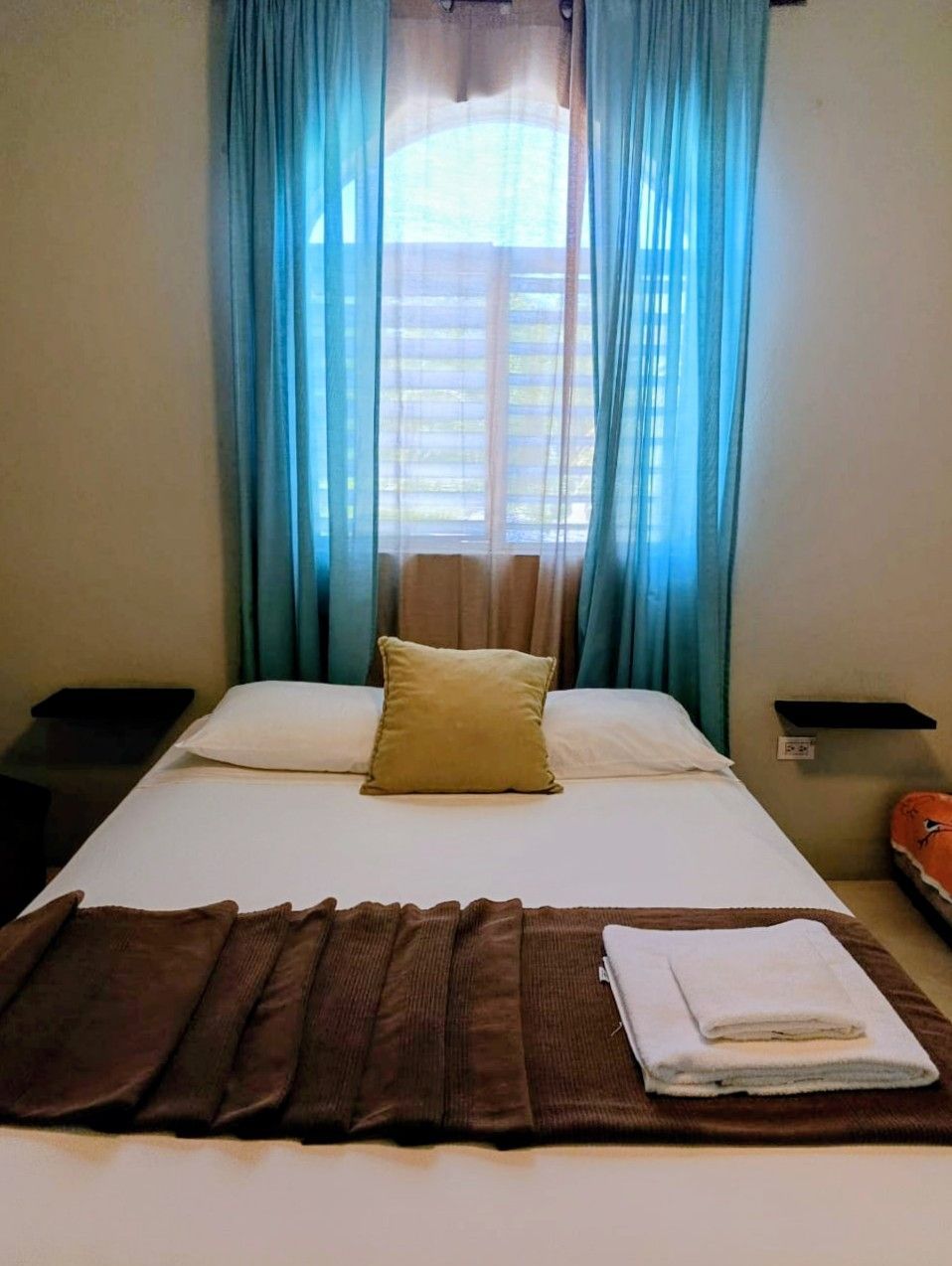 Bedroom with a bed, a window, and blue curtains.