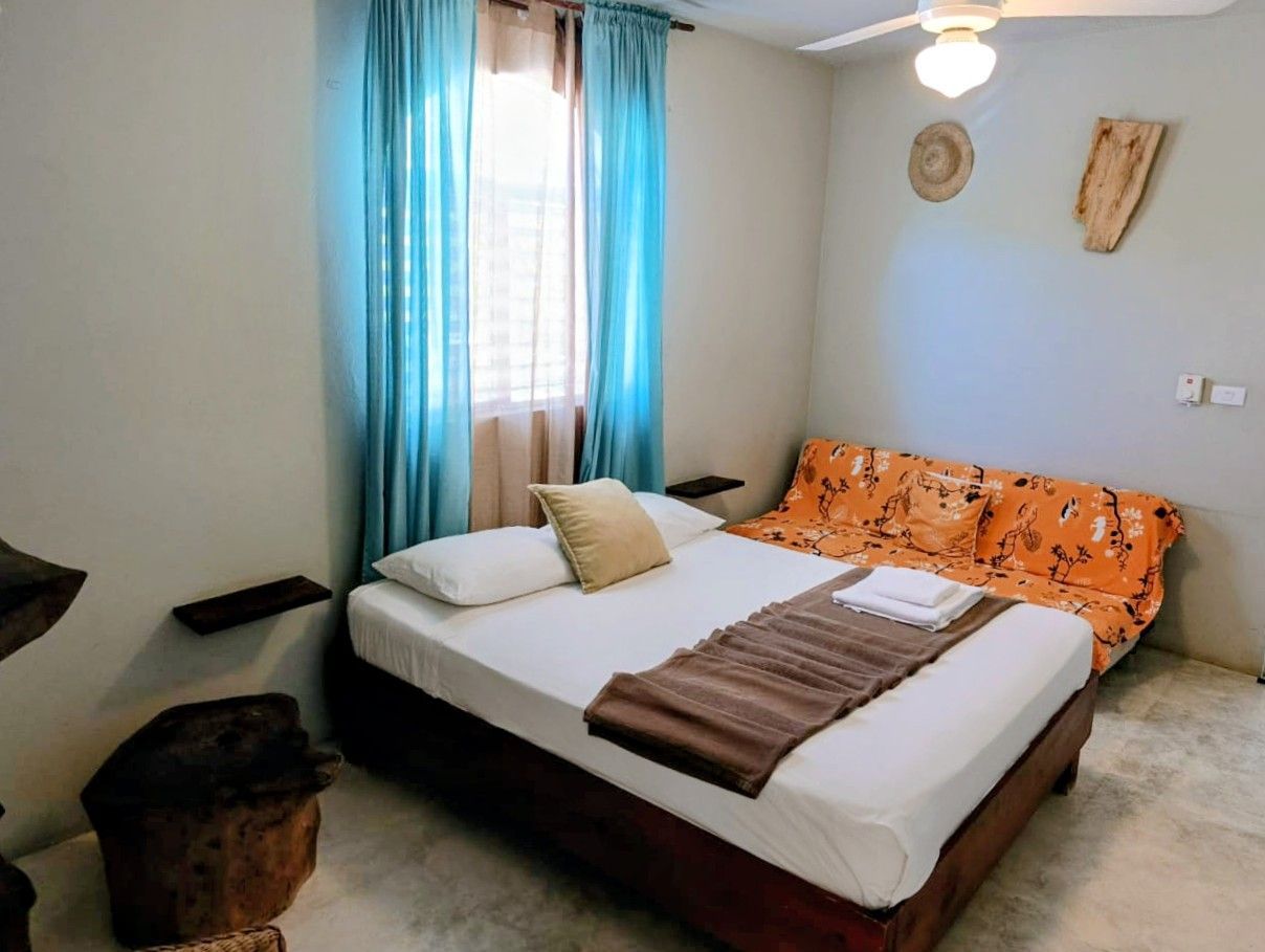 Bedroom with bed, futon, curtains, and rustic decor.