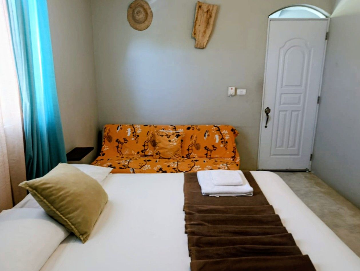 Bedroom with a bed, a yellow sofa, door, and decor on the walls.