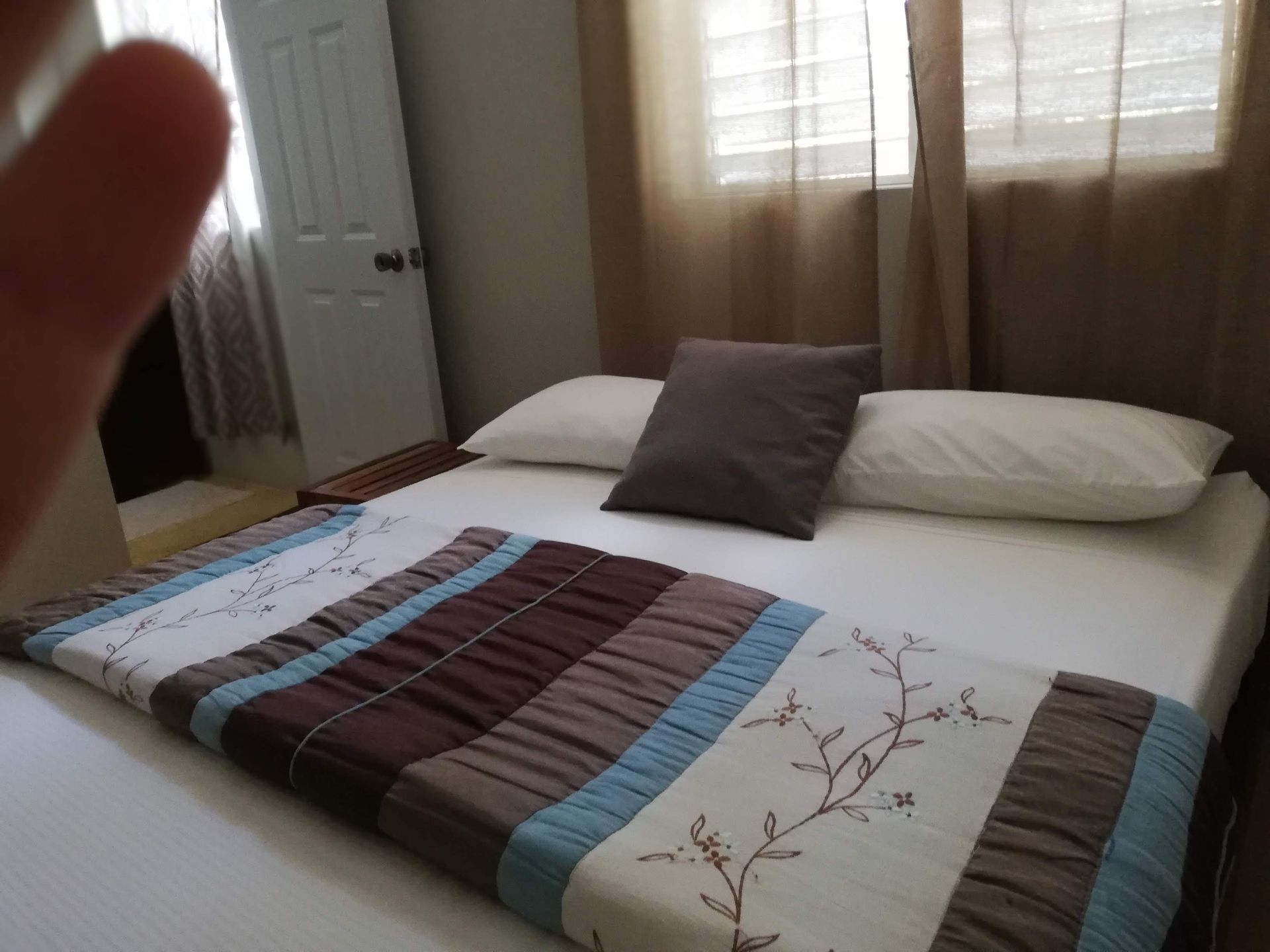 Bedroom with a bed, comforter, pillows, and a door. Brown, blue, and white colors.